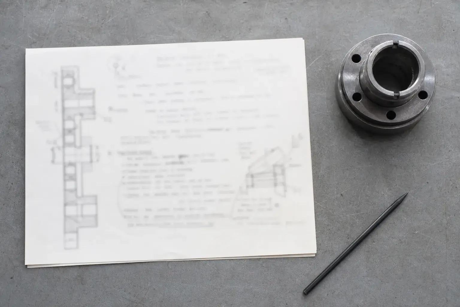 Document technique annoté au crayon, exigences soulignées, posé près d'une pièce de référence